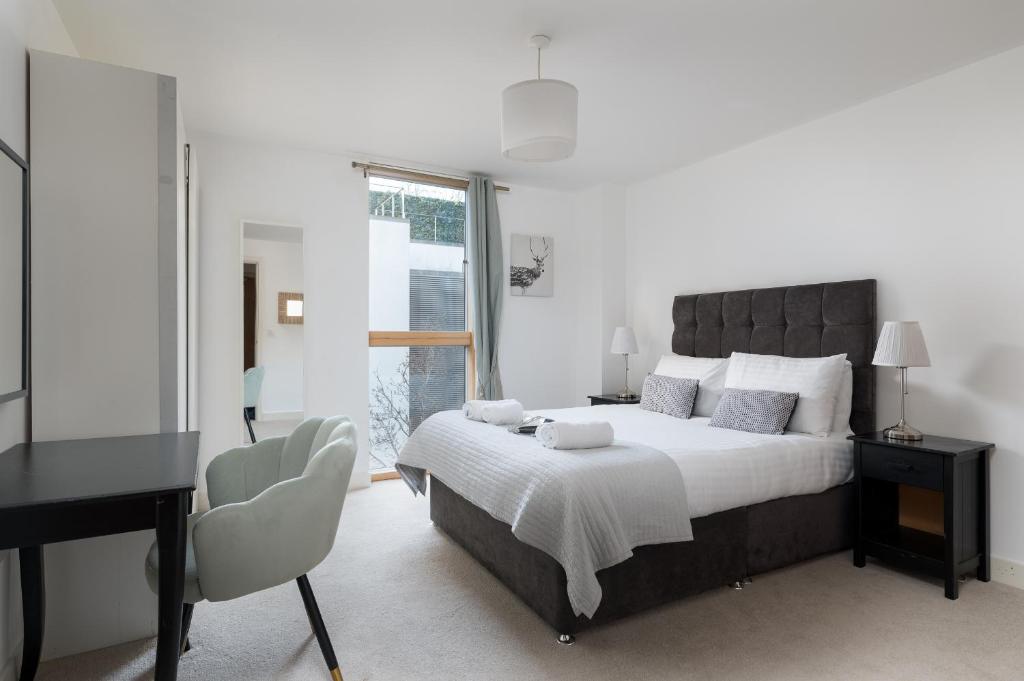 米尔顿凯恩斯City Stay Apartments - Vizion的一间卧室配有一张大床、一张桌子和一个窗户。