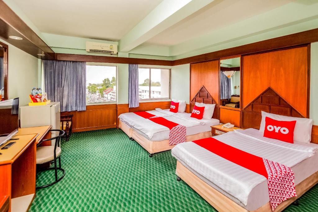 素叻OYO 441 Grand Thara Hotel的酒店客房配有两张床和一张书桌