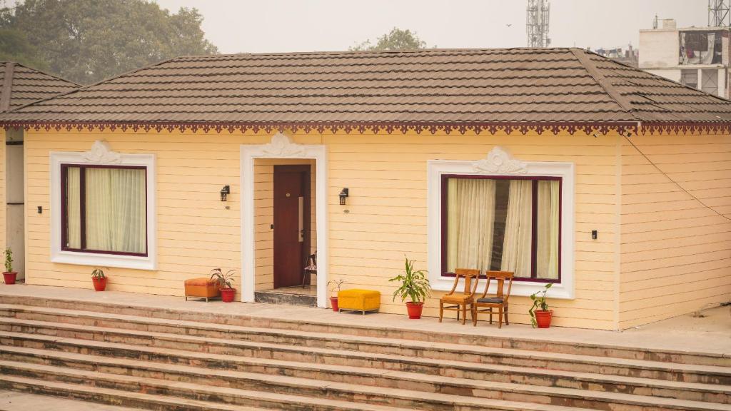 AyodhyaAyodhya haat Luxury Cottages的黄色的小房子,配有桌子和椅子