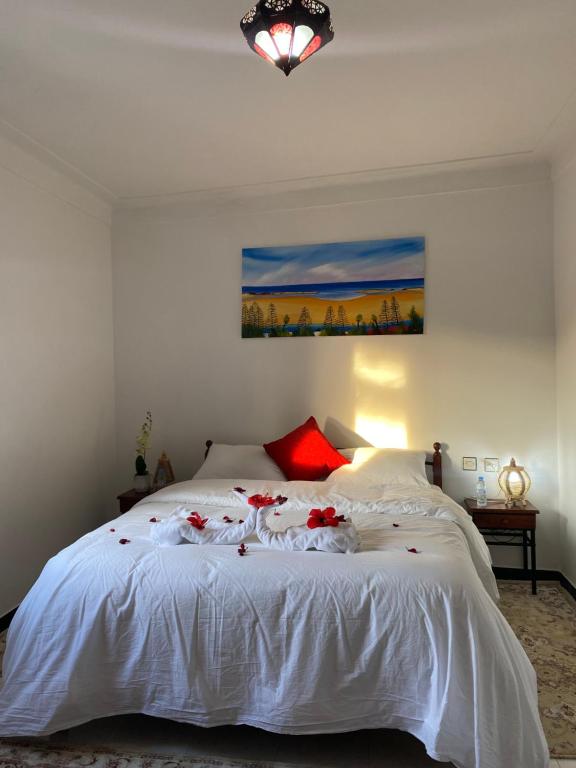 沃利迪耶Latifa house的卧室配有白色的床铺,上面有红色的鲜花