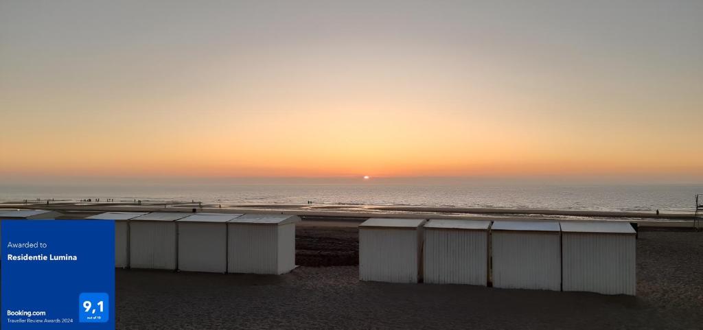 米德尔克尔克Residentie Lumina的日落时在海滩上存放一组容器