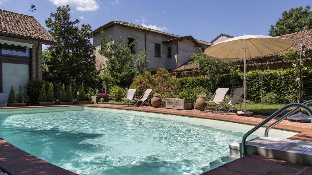 Truccazzano罗坎达圣安娜住宿加早餐旅馆的一个带遮阳伞和椅子的大型游泳池