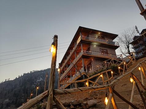 ToshPahadi Bliss Hostel ,Tosh的山上的木结构建筑,上面有灯