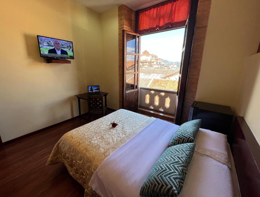 昆卡Floré Hotel Boutique Cuenca的一间卧室设有一张床、一台电视和一个窗口。