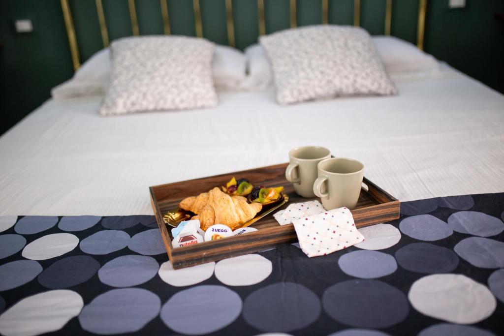 博洛尼亚Bologna Travel Suite的床上装有食物和杯子的托盘