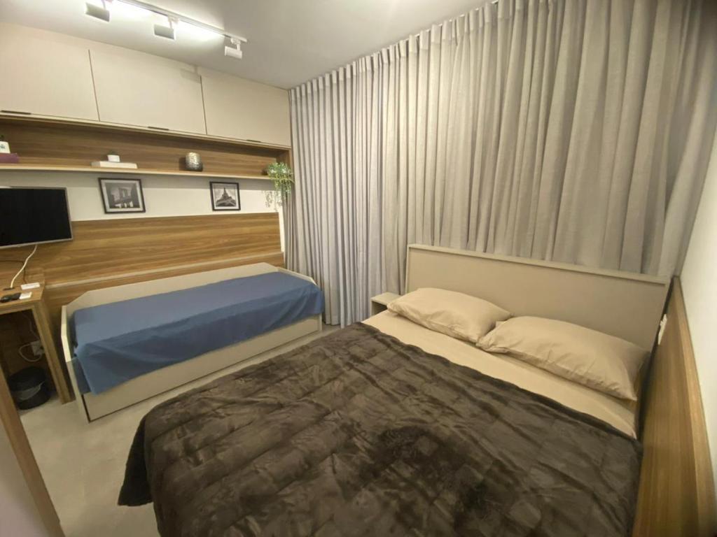 瓜鲁柳斯Studio 2 Patteo Helbor - MAIA的一间卧室配有一张床和一台电视