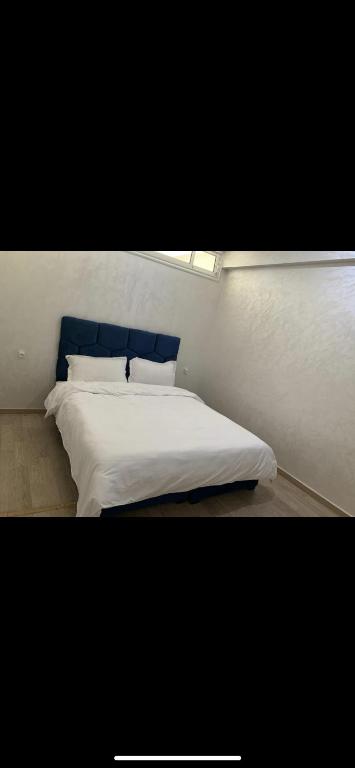 卡萨布兰卡Jolie appartement avec terrasse的一间卧室配有一张白色的床和蓝色床头板