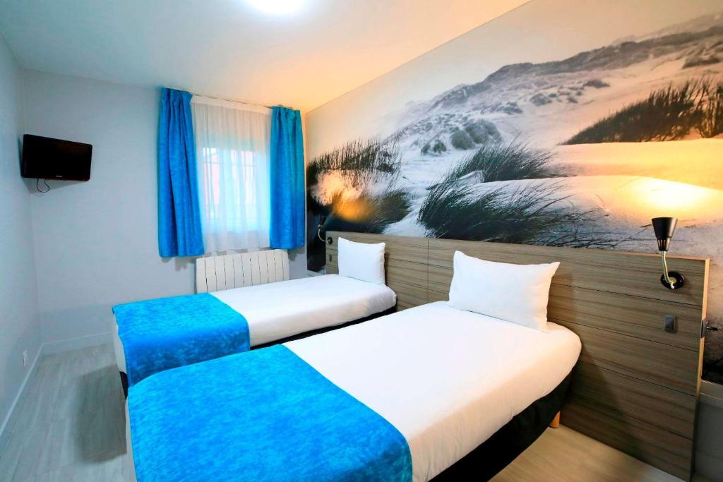 格拉沃利讷Brit Hotel Le Polder的墙上画画的房间里设有两张床