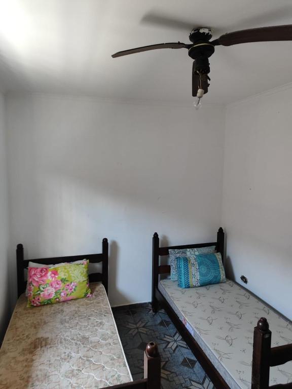 蒙加瓜Casa de praia em Mongaguá的配有吊扇的客房内的两张床
