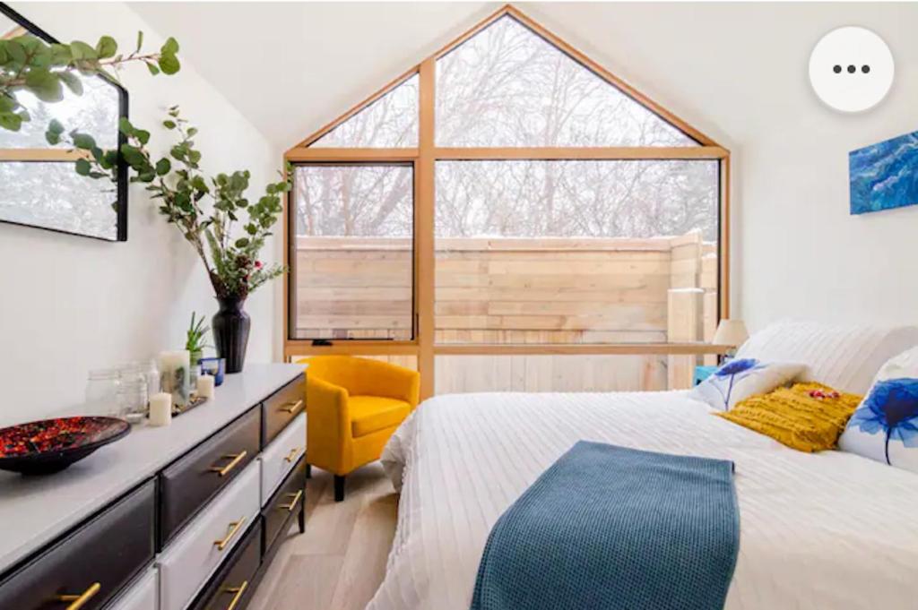 彼得伯勒Tiny House Haven的一间卧室设有床、窗户和黄色椅子