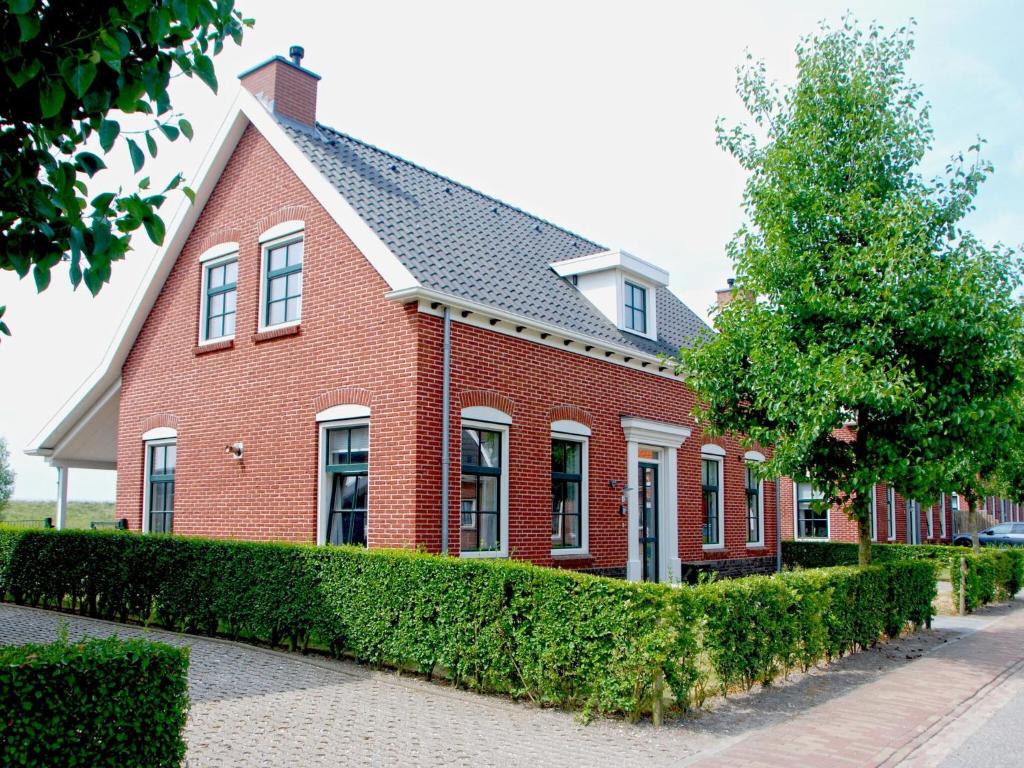 科莱恩斯普拉特Vacation home with sauna in Zeeland的前面有一棵树的红砖房子