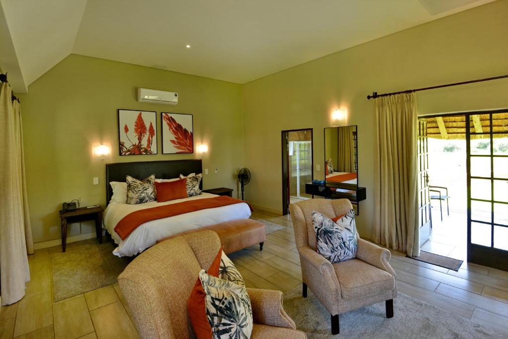 马加利斯堡African Hills Safari Lodge & Spa的一间卧室配有一张大床和两把椅子