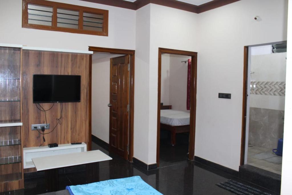 迈索尔Kamadhenu Homestay的一间设有床铺和墙上电视的房间