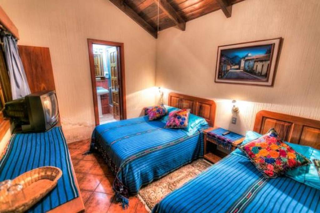 帕纳哈切尔Posada De Los Volcanes的一间带两张床的卧室和一台电视