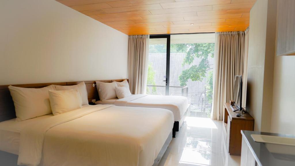 雅加达Nagomi Suites & Hotel的配有窗户的酒店客房内的两张床