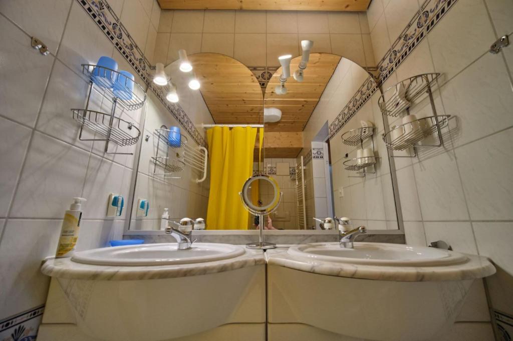 施库尔Chasa Panorama的一间带两个盥洗盆和大镜子的浴室
