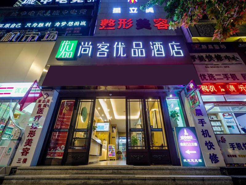 咸阳尚客优品咸阳人民路中心广场酒店的前方有 ⁇ 虹灯标志的建筑