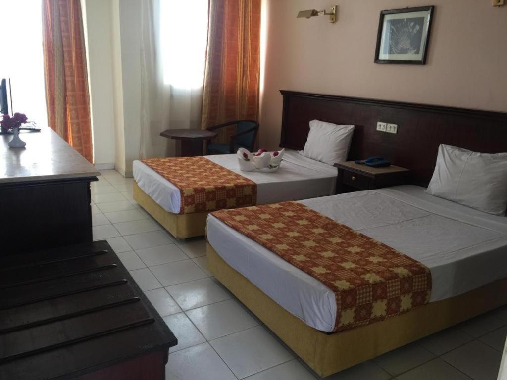 沙姆沙伊赫Regency Lodge Hotel的酒店客房设有两张床和一张桌子。