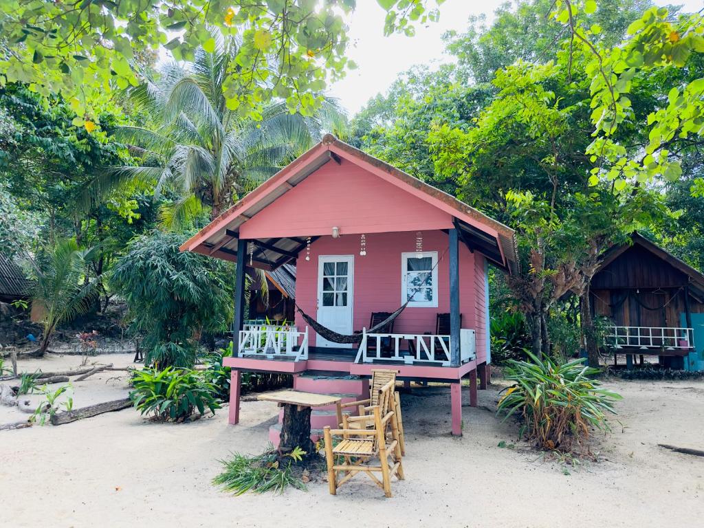 昌岛Full Moon Bungalow Resort Koh Chang Ranong的海滩上带桌椅的粉红色小房子