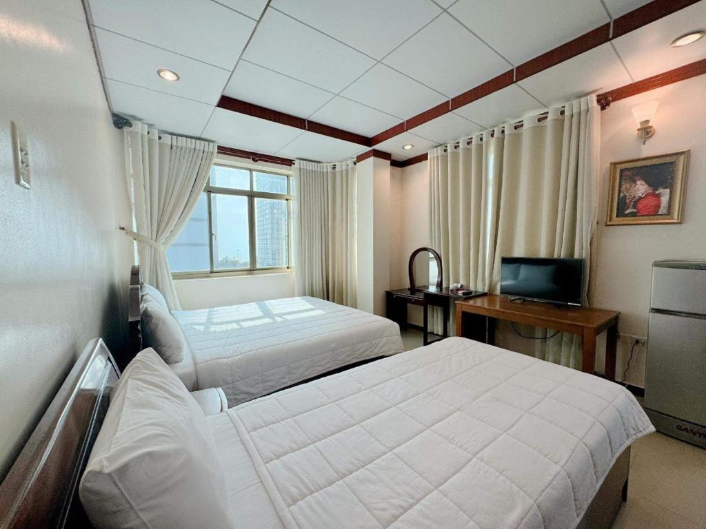 头顿Phúc Đạt Hotel的一间卧室配有两张床、一张桌子和一台电视。