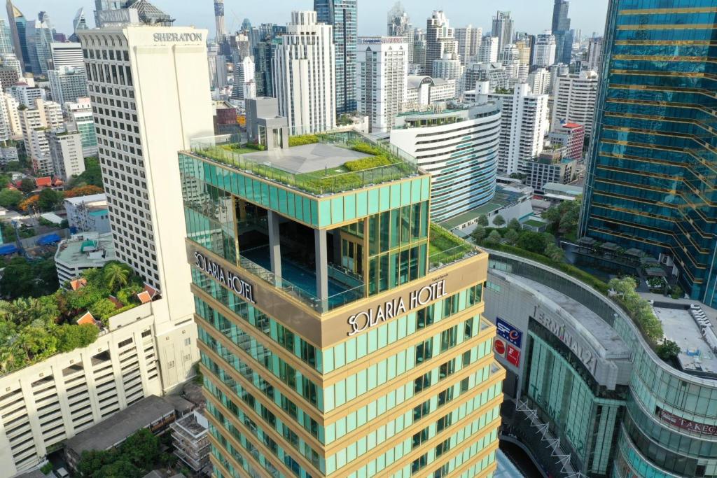 曼谷曼谷索拉利亚西铁饭店的一座高大的建筑,有绿色屋顶,位于城市