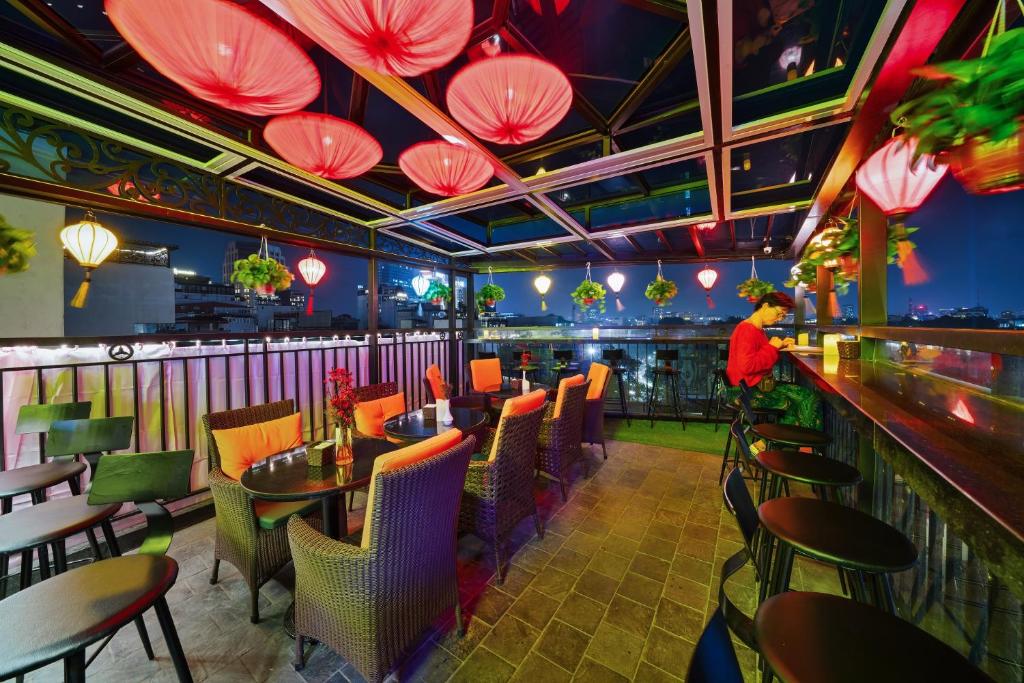 河内Bella Premier Hotel & Rooftop Skybar的餐厅设有酒吧,配有桌椅