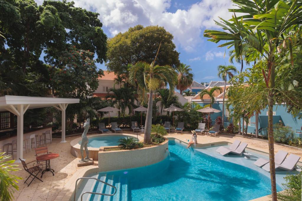 威廉斯塔德Kura Botanica Hotel的棕榈树和椅子的度假村的游泳池