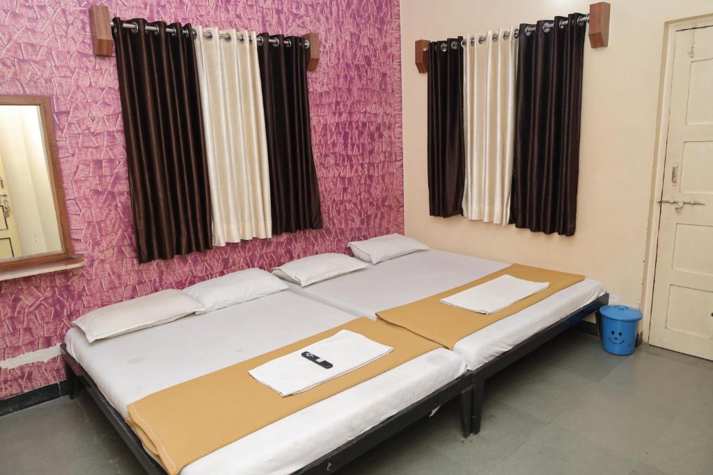 舍地Hotel laxminarayan的粉红色墙壁的房间里一张床位