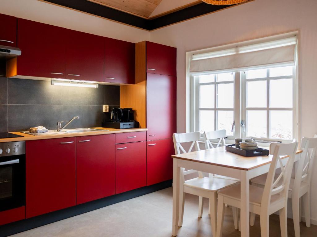 De VeenhoopHoliday Home Natuurlijk de Veenhoop by Interhome的厨房配有红色橱柜和桌椅