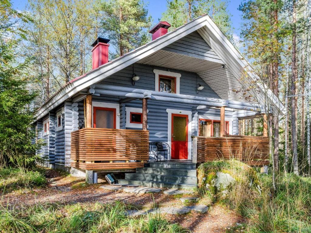 SavilahtiHoliday Home Ulpukka by Interhome的树林里一扇红色门的灰色房子