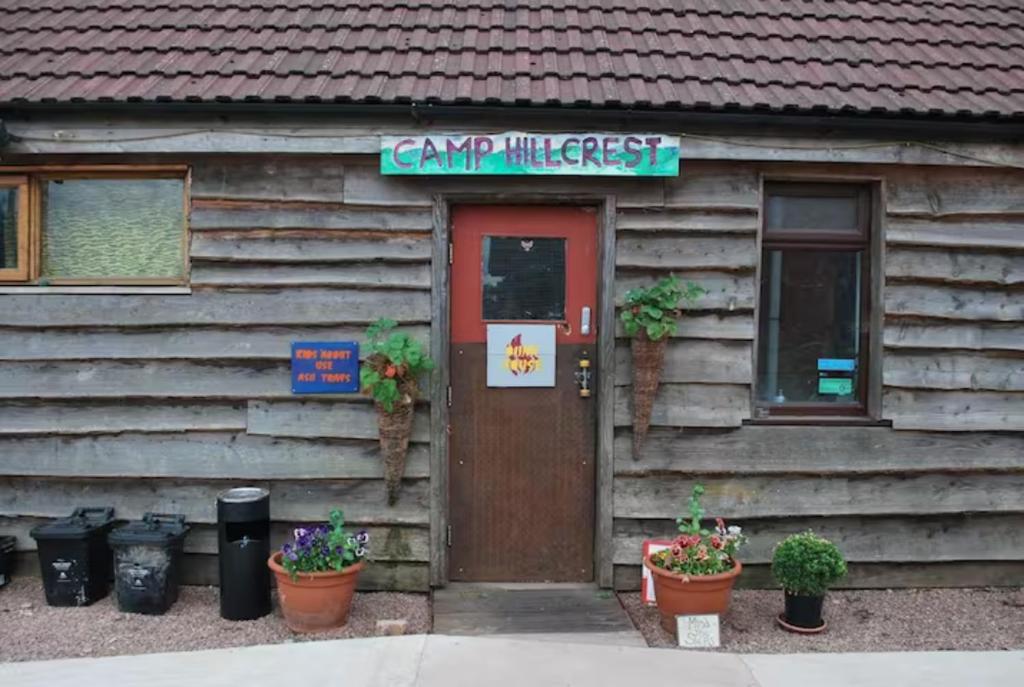 Camp Hillcrest Bunkhouse的小屋的门上和植物上都标有标志