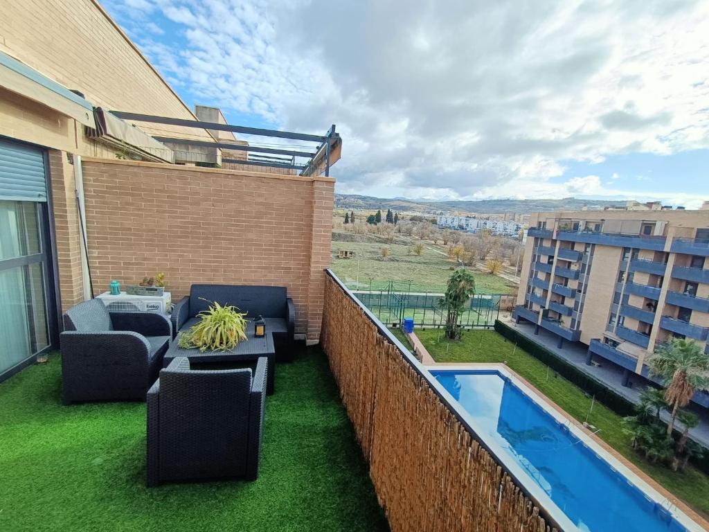 格拉纳达Acogedora habitación privada en Villa Mayka的阳台设有庭院家具和游泳池。