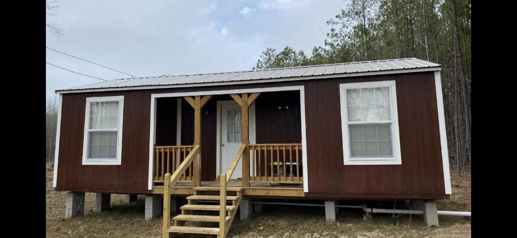 西点Louisiana State Cabin的一个小房子,设有门廊和窗户