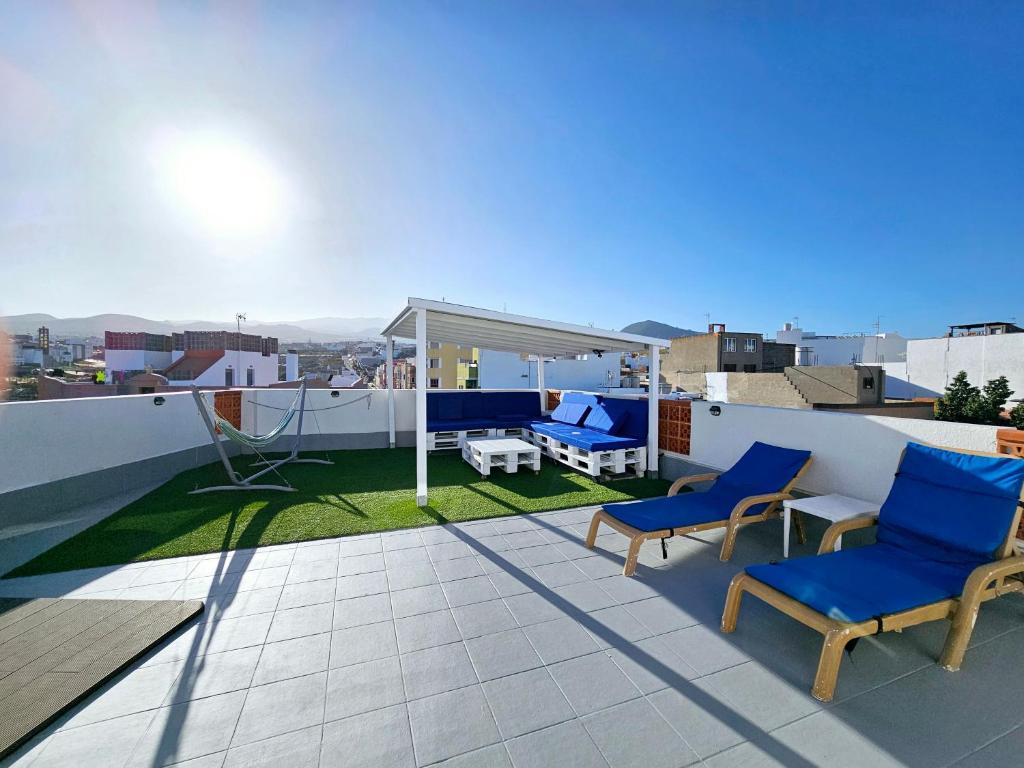 特尔德St George's Apartments - Gran Canaria的阳台配有蓝色的椅子和一张屋顶桌子。