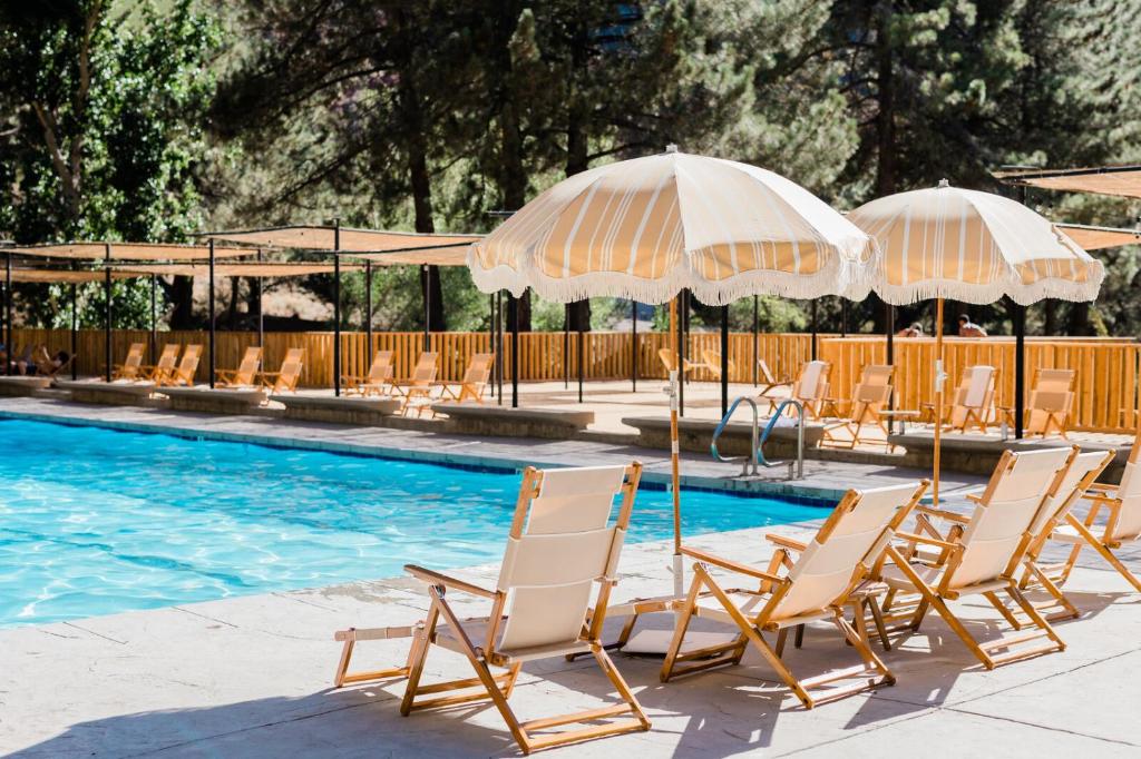 ValyermoHuttopia Paradise Springs的一组椅子和遮阳伞,位于游泳池旁