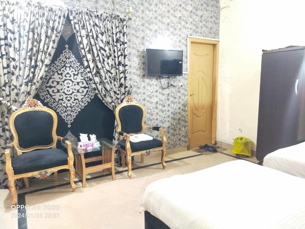 拉合尔Hotel Eden Plus Lahore的一间卧室配有两把椅子和一台墙上的电视