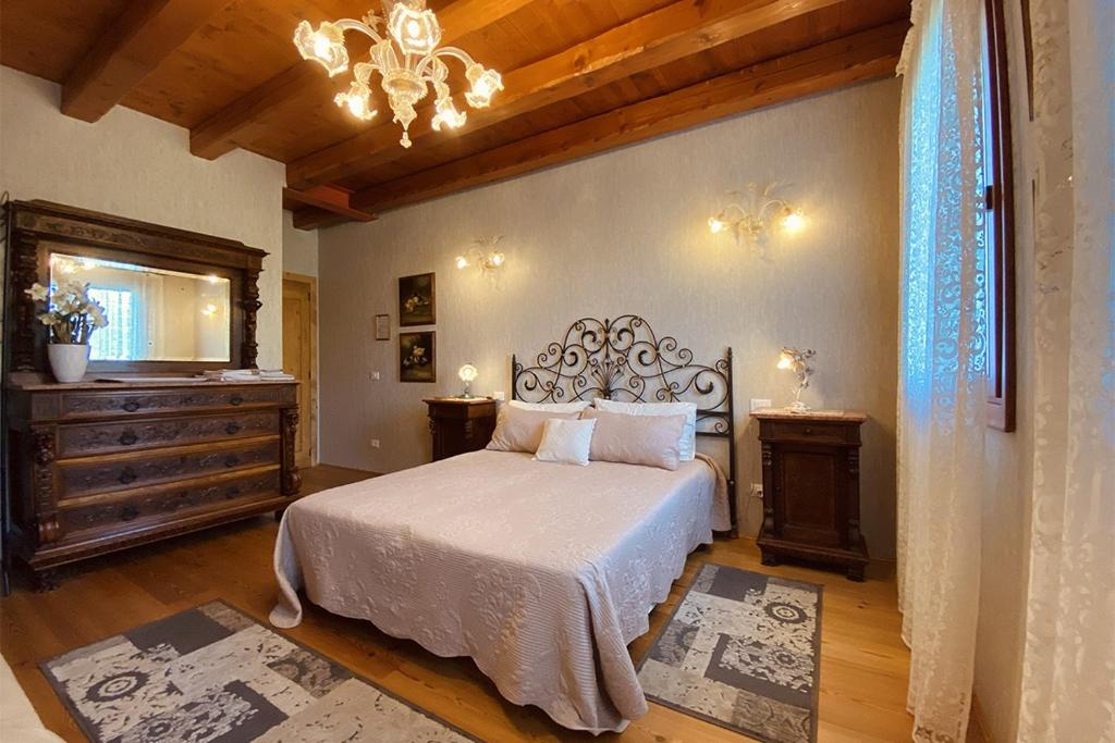 圣米凯莱亚尔塔利亚门托维奇奥费恩尼尔酒店的一间卧室配有一张床和一个吊灯
