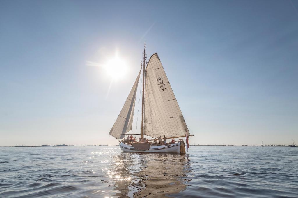WoudsendSail Events Friesland的水面上的帆船,太阳在后面