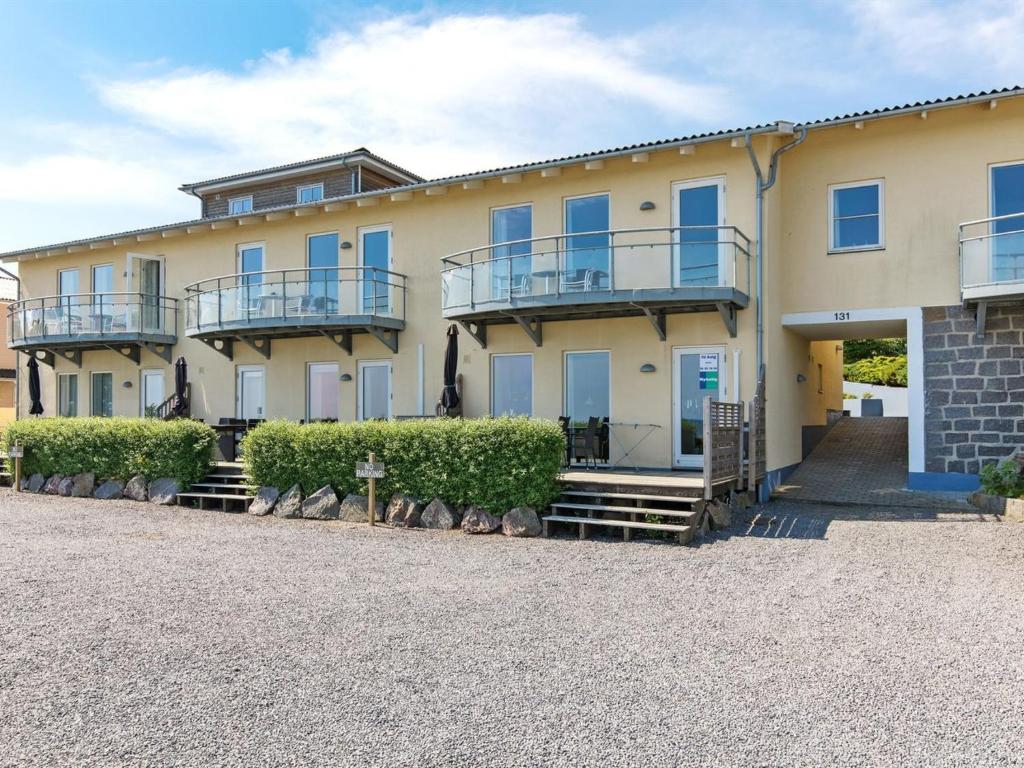 阿灵厄Apartment Henna - 50m from the sea in Bornholm by Interhome的带阳台和灌木的大黄色建筑