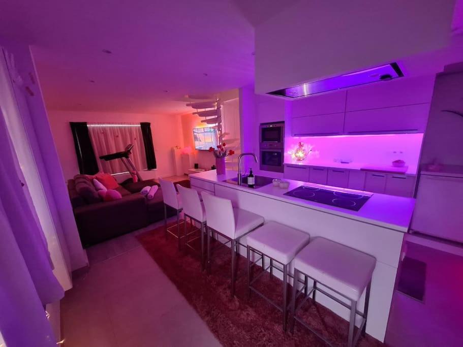 隆德泽尔Relax House B&B Londerzeel的厨房配有紫色照明,酒吧配有凳子