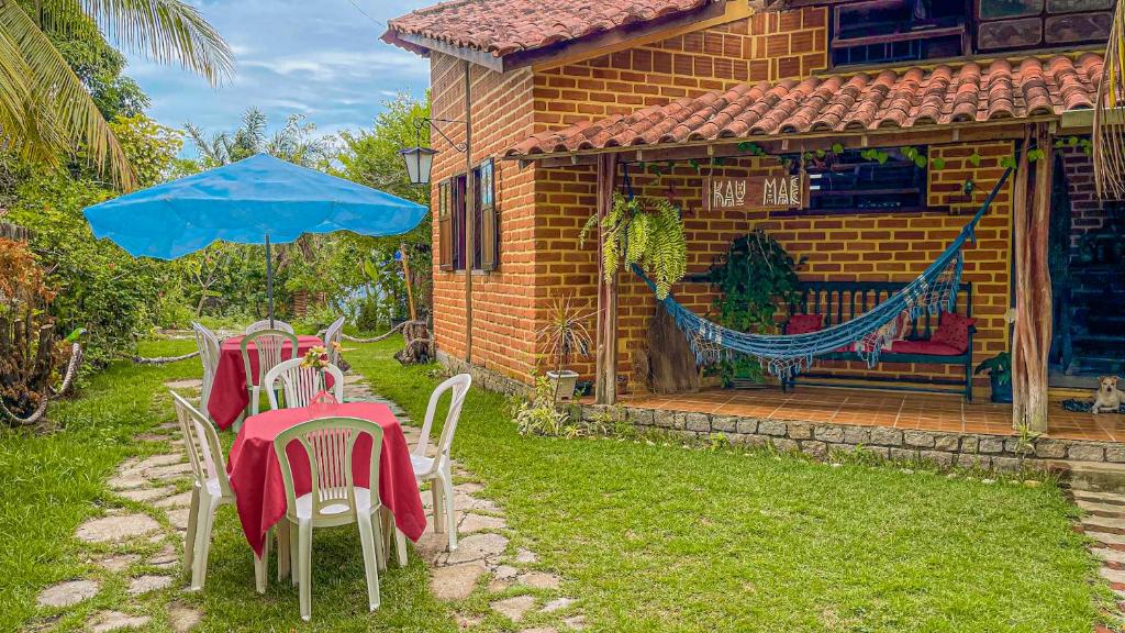 桑塔克鲁茨卡巴利亚KauMaê的院子里设有两张桌子、椅子和一把蓝色雨伞