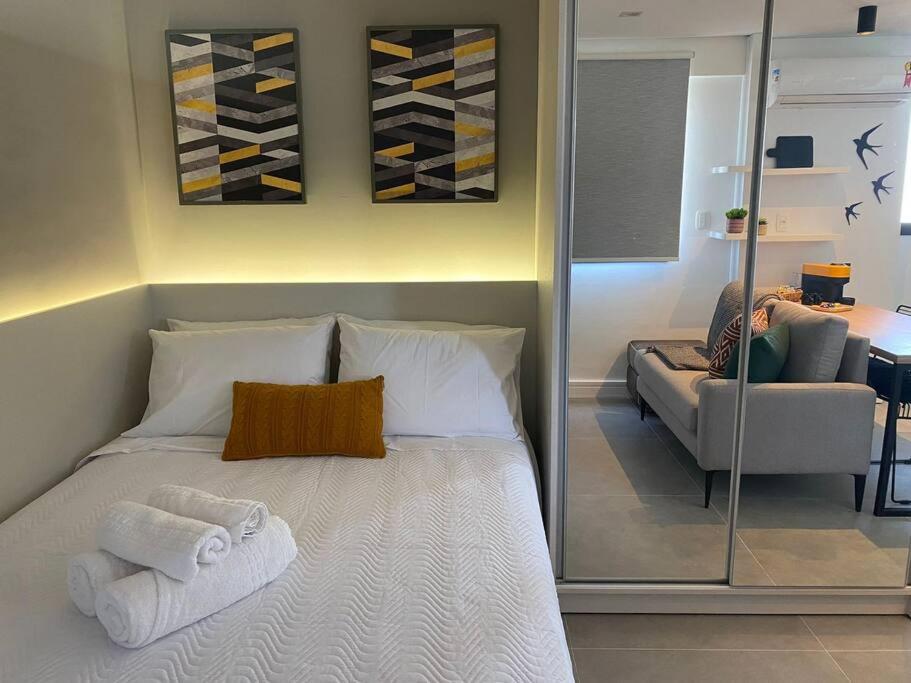 阿雷格里港Super compacto aconchegante.的一间卧室配有带毛巾和沙发的床