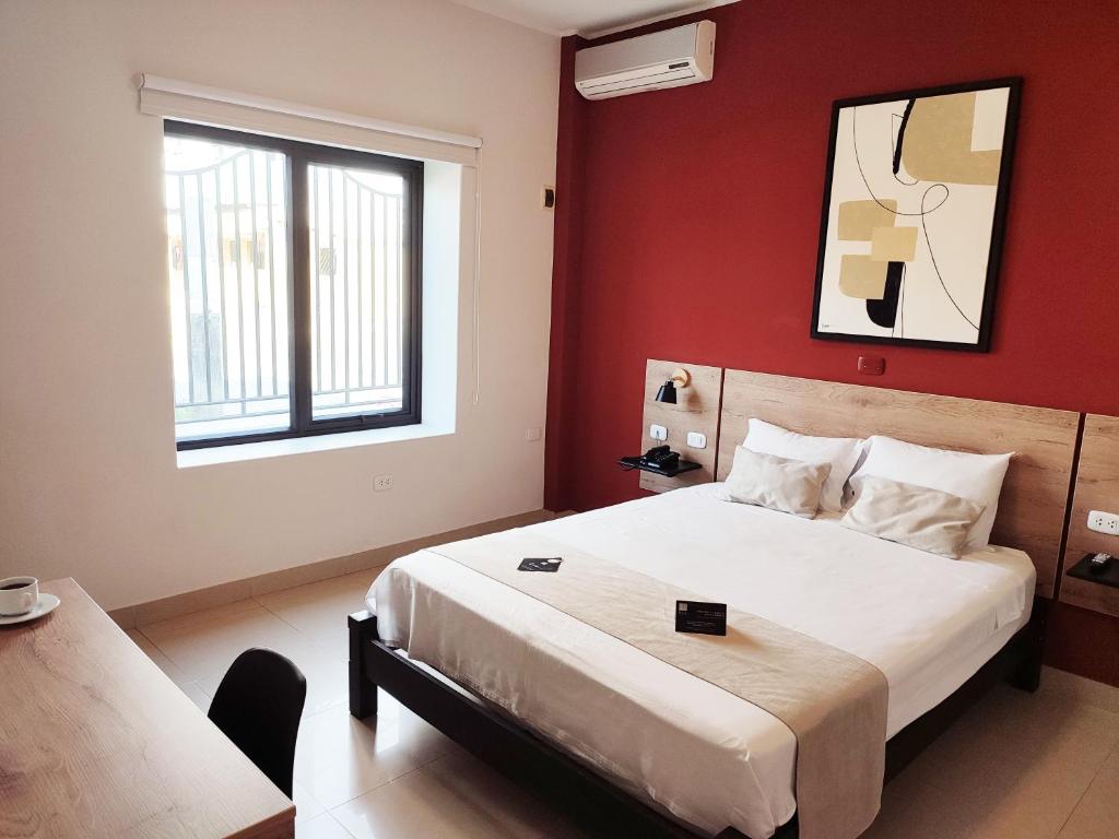 塔拉拉Rua Hoteles Talara的一间卧室设有一张带红色墙壁的大床
