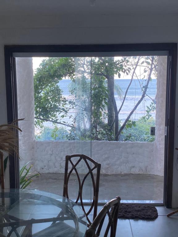 弗洛里亚诺波利斯Casa beira do mar的一个带大窗户的房间里,一张玻璃桌子和椅子