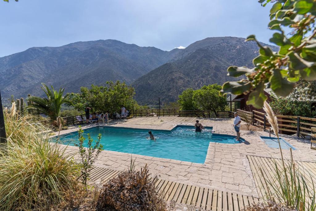 圣何塞德迈波Las lomitas de Guayacan, Cabañas y Spa的一座游泳池,里面的人有山,背景