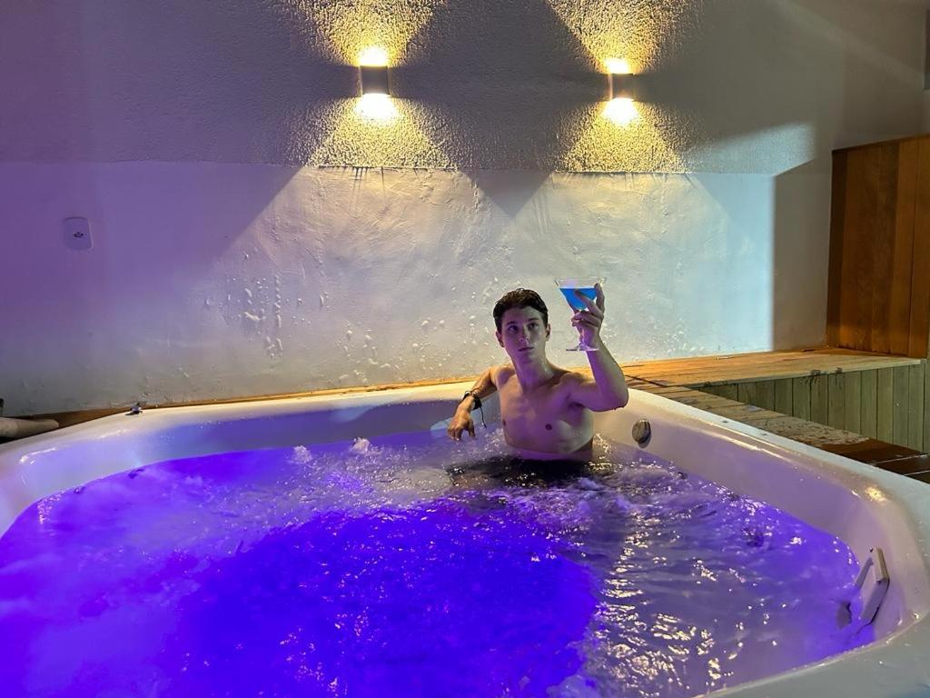 卡波布里奥Pousada Velas do Forte的男人在装满紫色水的浴缸里