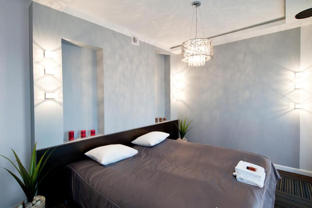 罗兹Młoda Europa的一间卧室配有一张带两个枕头的床和吊灯。