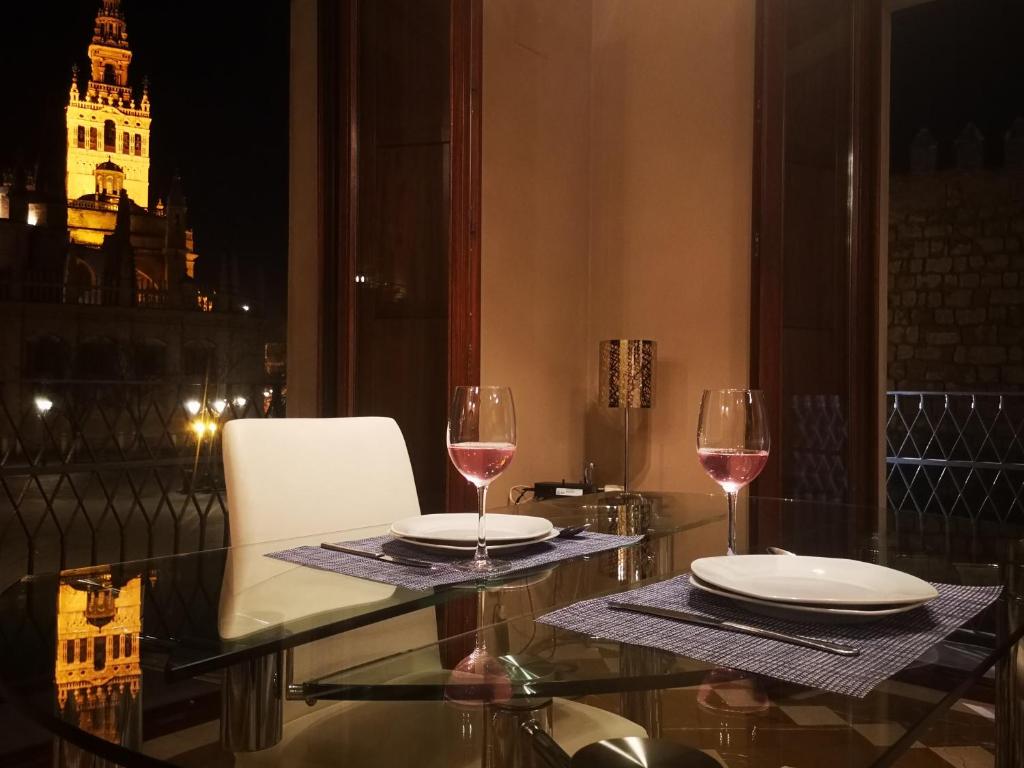 塞维利亚Luxury Apartment with views to Alcazar, Cathedral and Giralda.的阳台上的桌子和两杯葡萄酒