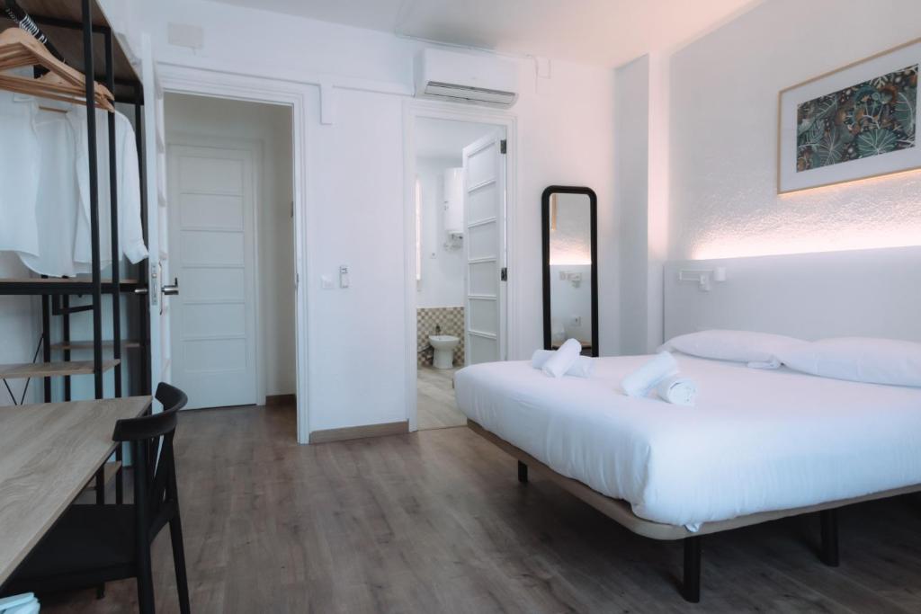 瓦伦西亚Clink Rooms & Flats的白色卧室配有床和桌子