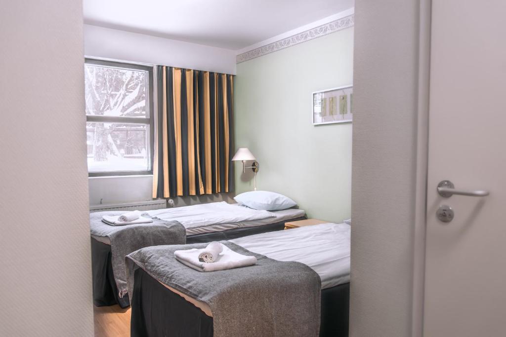 埃斯波Hotelli Tiiliriihi的两张位于酒店客房的床,配有毛巾
